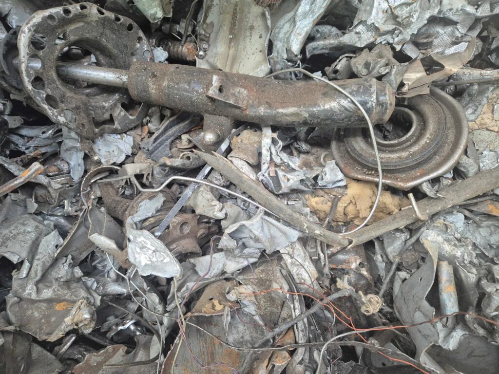 Close-up of shredded ferrous scrap with a shock absorber, springs, sheet steel and wires